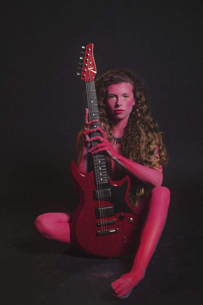 Hannah Wicklund seated with her red guitar